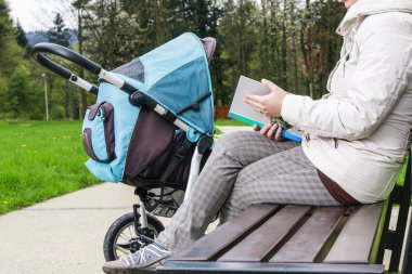 Kadın bir kitap okurken çocuk arabası ile