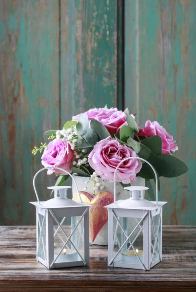 Two white iron lanterns and bouquet of pink roses in the backgro — Stock Photo, Image