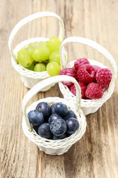 Manden met vruchten: frambozen, bosbessen en druiven. — Stockfoto
