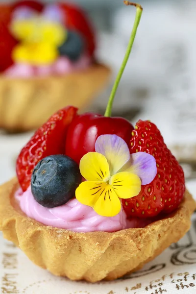 Cupcakes mit frischen Früchten und essbaren Blumen. — Stockfoto