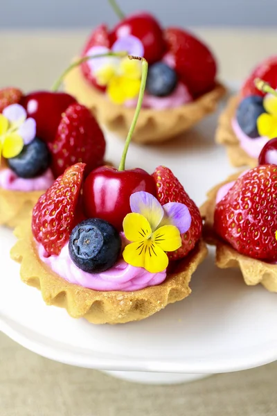 Cupcakes mit frischen Früchten und essbaren Blumen. — Stockfoto