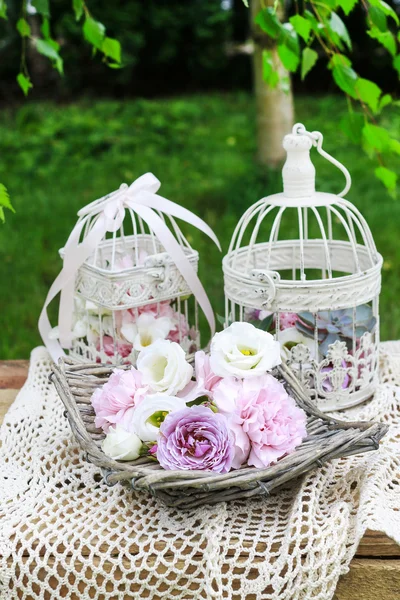 Basket of flowers and vintage bird cages with flowers inside.
