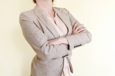 Şık takım elbiseli kadın kollarını kavuşturmuş duruyor. Vücut dili, kendine güvenen kişi..