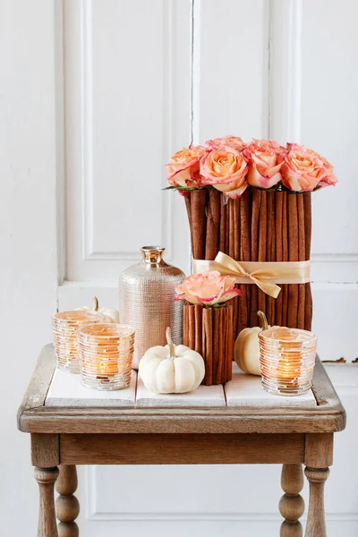 Floral arrangement with roses and cinnamon sticks stands on the table. Party decor