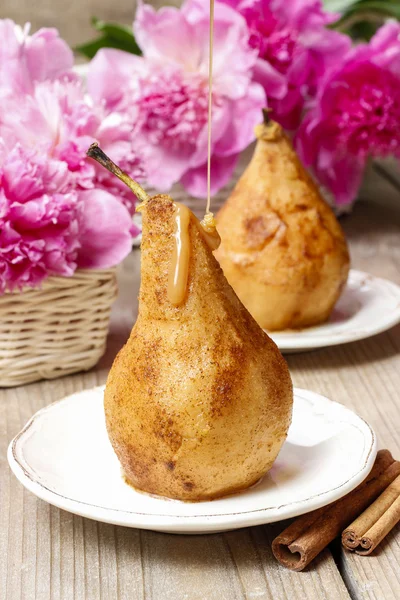 Birne mit Karamell, schöne rosa Pfingstrosen im Hintergrund — Stockfoto