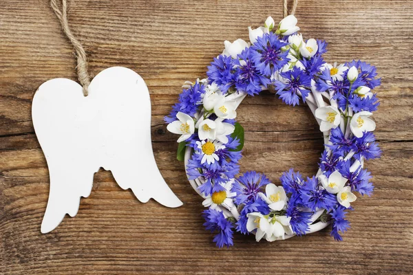 White wicker wreath decorated with flowers, and wooden angel win — Stock Photo, Image