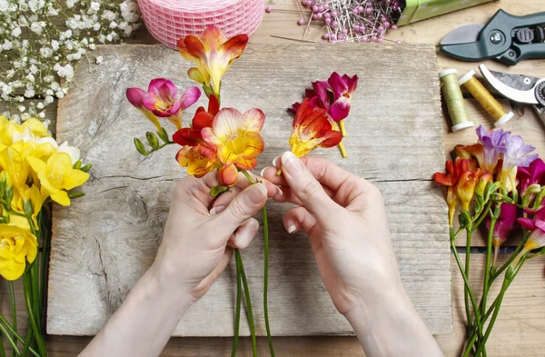 Florista no trabalho. Mulher fazendo buquê de flores freesia primavera — Fotografia de Stock