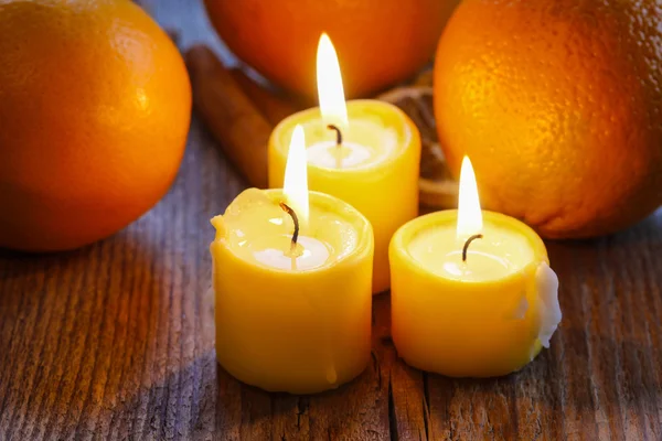 Красивые свечи и сочные апельсины на джутовой скатерти — стоковое фото