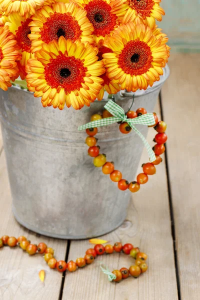 Strauß orangefarbener Gerbera-Gänseblümchen im silbernen Eimer auf Holzlasche — Stockfoto