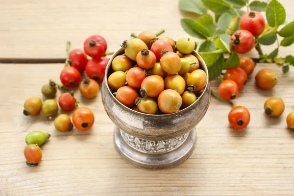 Vintage striped box of rose hip fruits on wooden table — Stock Photo, Image