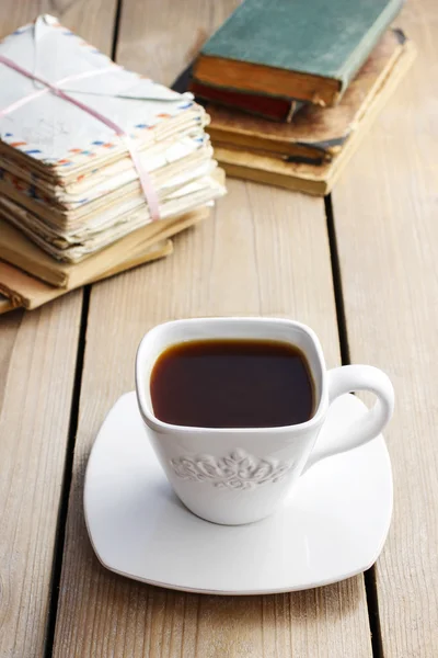 Tazza di caffè sul tavolo di legno. Libri d'epoca e pile di lettere — Foto Stock