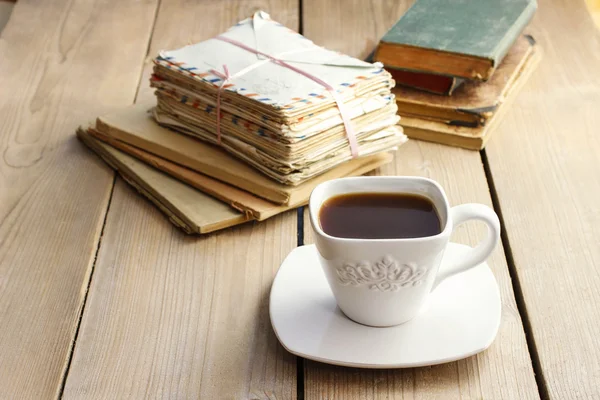 Kopp kaffe på träbord. Vintage books och hög med bokstäver — Stockfoto