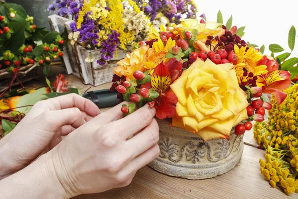 Fiorista al lavoro: donna che fa bouquet di rose arancioni e autunno — Foto Stock