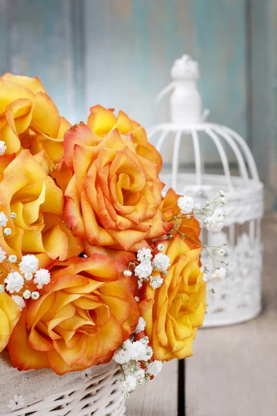 在白色的柳条篮子和老式 bir 橙色玫瑰的花束 — 图库照片