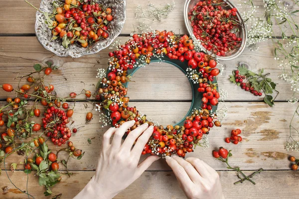 Florist at work: woman making rose hip and hawthorn wreath — Stock Photo, Image