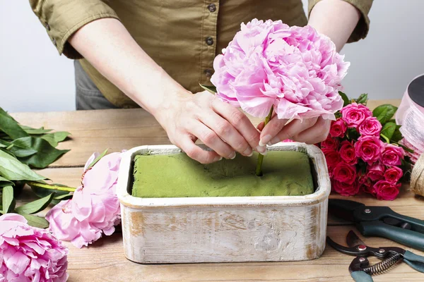 Florista no trabalho: mulher fazendo decoração floral de peônias rosa — Fotografia de Stock