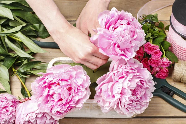 Florista no trabalho: mulher fazendo decoração floral de peônias rosa — Fotografia de Stock