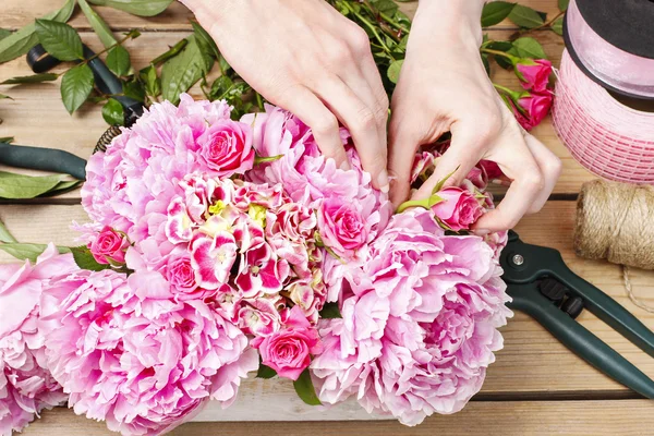 Bloemist op het werk: vrouw florale decoratie van roze pioenrozen maken — Stockfoto
