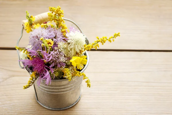 Bouquet of wild flowers on brown wooden background