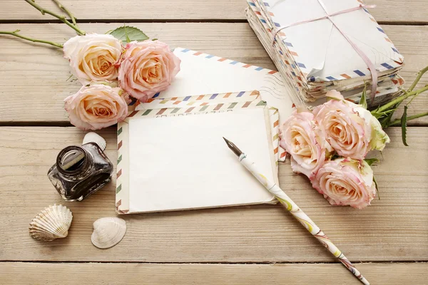 Vintage brieven, rozen en fles inkt op houten tafel. — Stockfoto