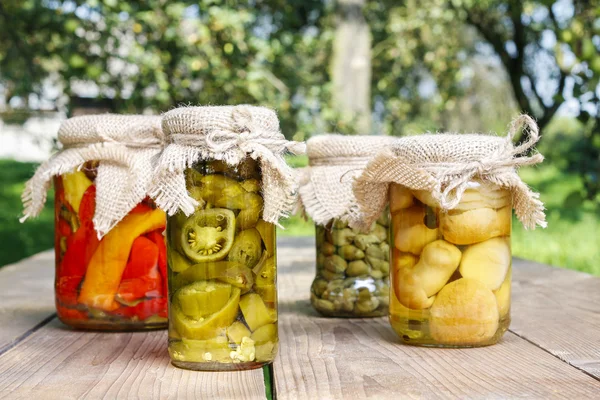 Jars of preserves on wooden table in the garden — Stock Photo, Image