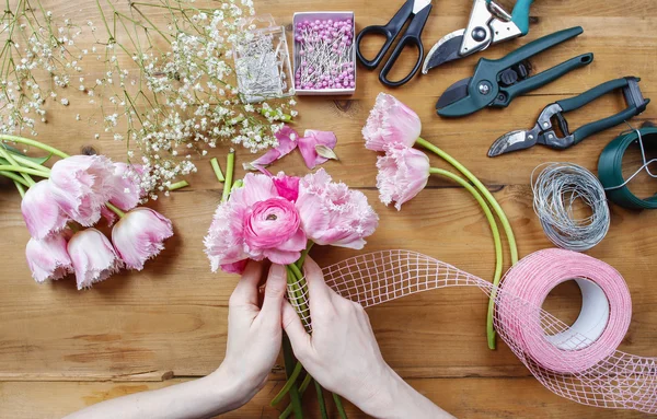 Florista no trabalho. Mulher fazendo buquê de buttercup persa rosa — Fotografia de Stock