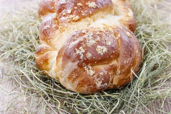 Loaf of sweet christmas bread lying on hay — Stock Photo, Image