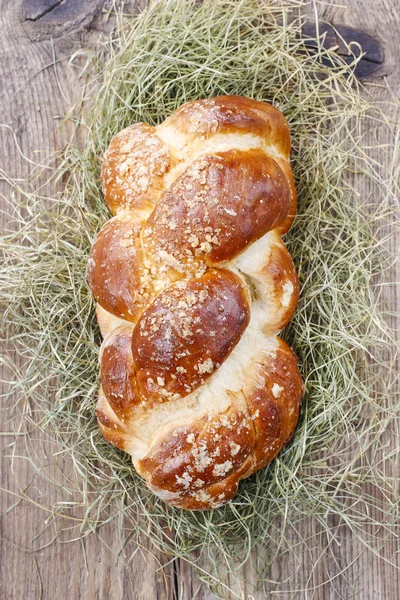 Loaf of sweet christmas bread lying on hay — Stock Photo, Image