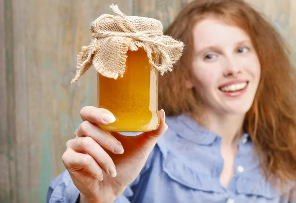 Happy young woman holding glass jar of honey — Stock Photo, Image