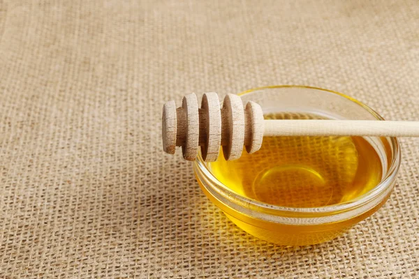 Glass bowl of honey on jute background — Stock Photo, Image