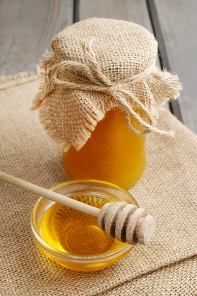 Glass bowl of honey on jute background — Stock Photo, Image