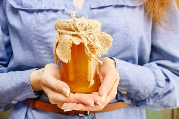 Mujer sosteniendo frasco de vidrio de miel —  Fotos de Stock