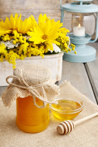 Pot met honing op houten tafel, boeket met zonnebloemen in de backg — Stockfoto