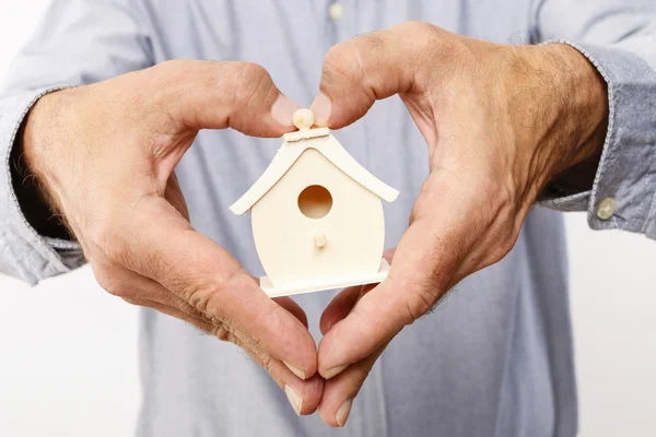 Hombre sosteniendo pequeña casa de madera — Foto de Stock