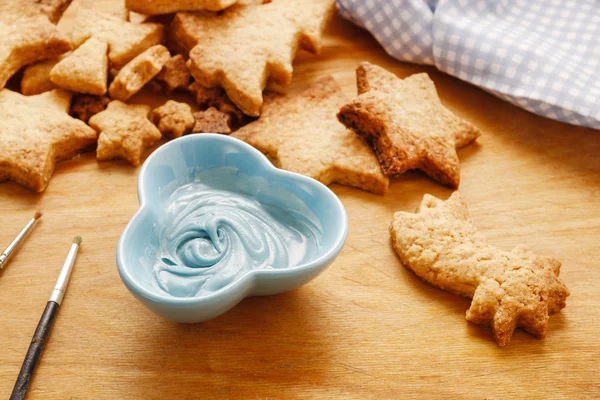 Decorating gingerbread cookies with blue and white icing. — Stock Photo, Image