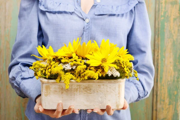 Frau hält Arrangement von Sonnenblumen in Holzkiste Stockbild