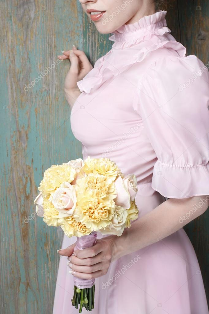 Woman holding bouquet of yellow carnation and pink pastel roses