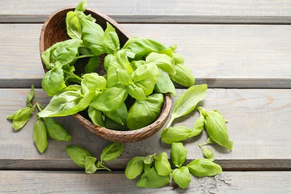 Bowl of basil leaves on wooden table — Stock Photo, Image