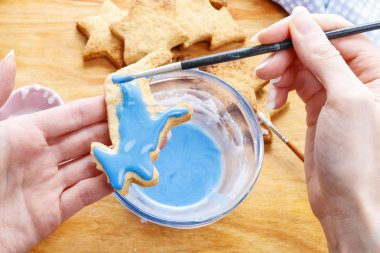 Decorating gingerbread cookies with blue and white icing.  clipart