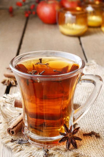 Glass of hot steaming tea among christmas decorations — Stock Photo, Image