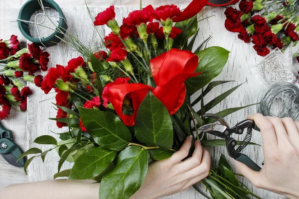 Florist at work. Woman making bouquet of red carnations — Stock Photo, Image