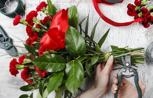 Florist bei der Arbeit. Frau macht Strauß roter Nelken — Stockfoto