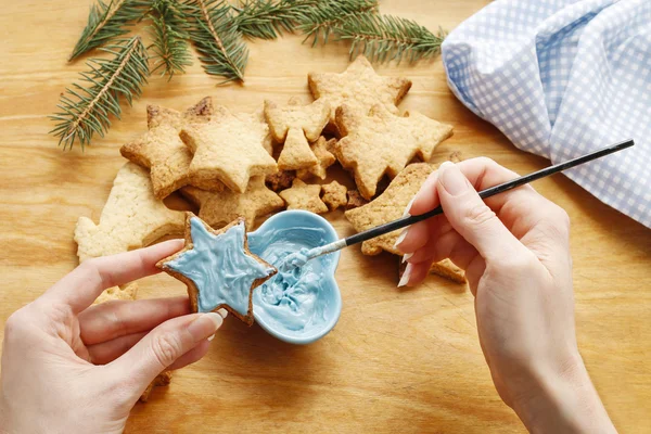 Decorating gingerbread cookies with blue and white icing. — Stock Photo, Image