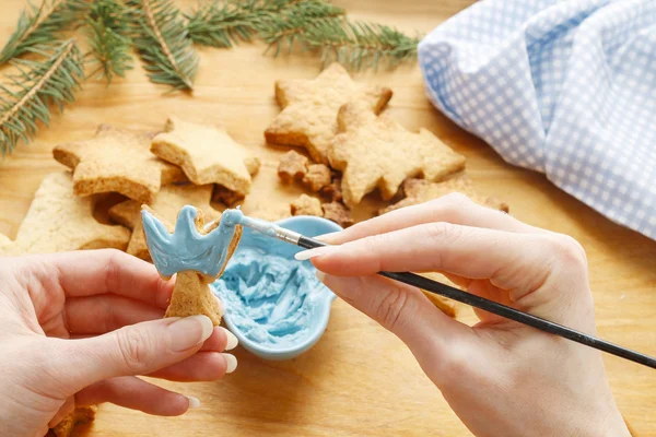 Decorating gingerbread cookies with blue and white icing. — Stock Photo, Image