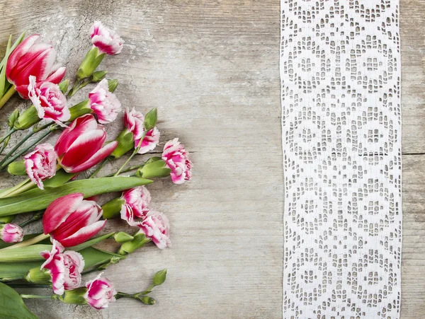 Smukke lyserøde tulipaner og nelliker på træ - Stock-foto