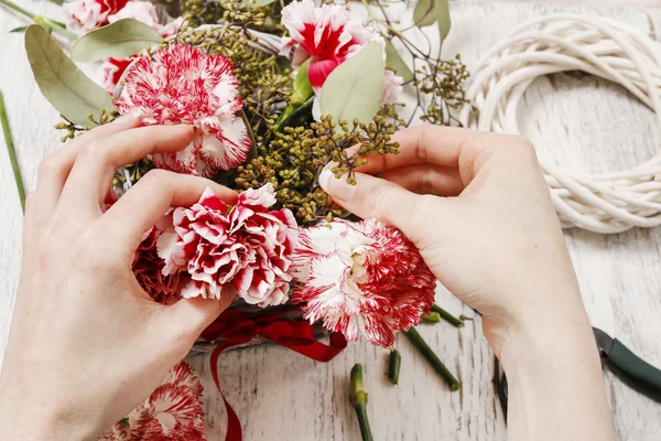 Mulher fazendo buquê de flores de cravo vermelho e branco — Fotografia de Stock