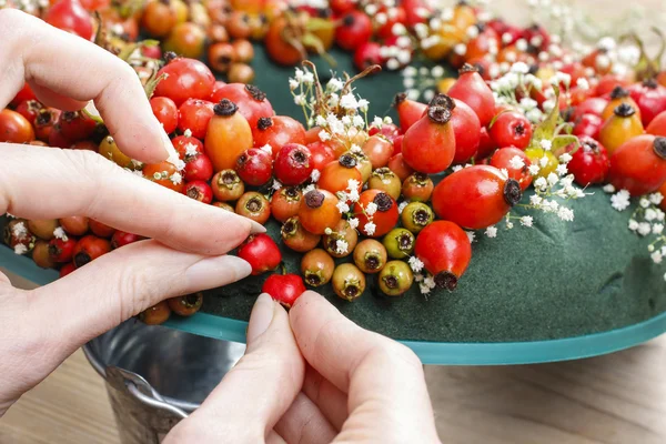 ローズヒップ、サンザシ、ローワンとドアの花輪を作る手順 — ストック写真