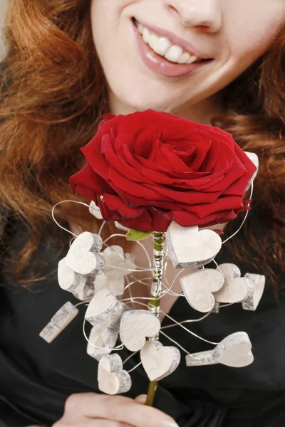 Mulher segurando rosa vermelha decorada com corações de madeira — Fotografia de Stock