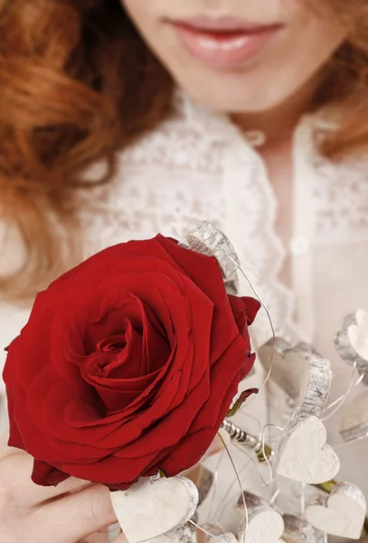 Женщина с красной розой, украшенной деревянными сердцами — стоковое фото