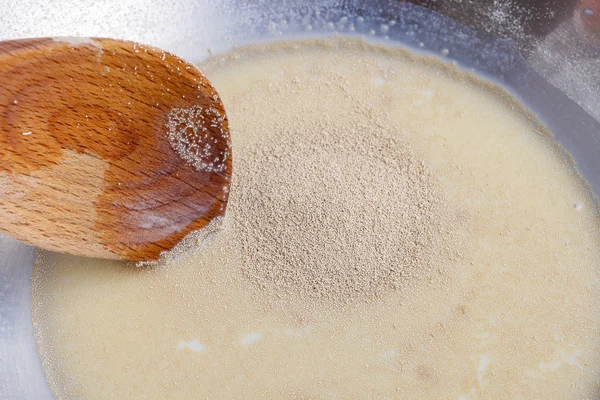 Как сделать дрожжевое тесто - шаг за шагом: смешать сухие дрожжи с молоком — стоковое фото
